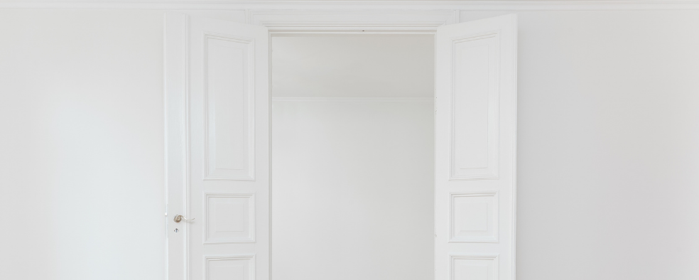 En åben og hvid indvendig dør i et lyst hjem med hvide vægge
